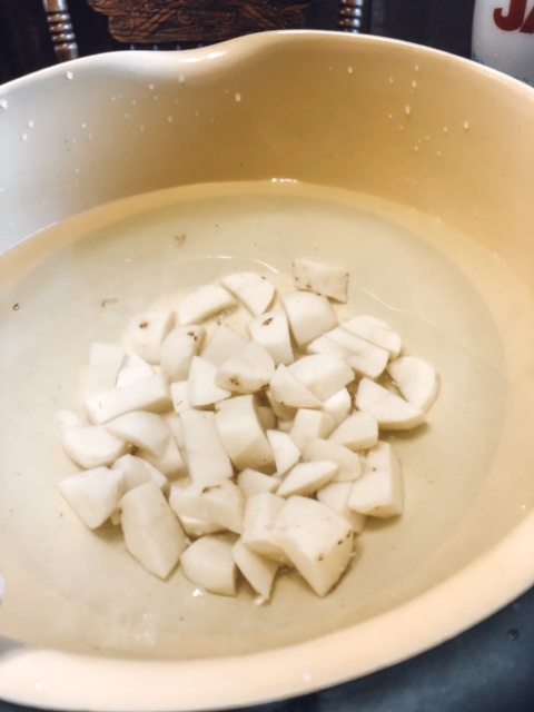 Cut up potatoes in a bowl of cold water. 